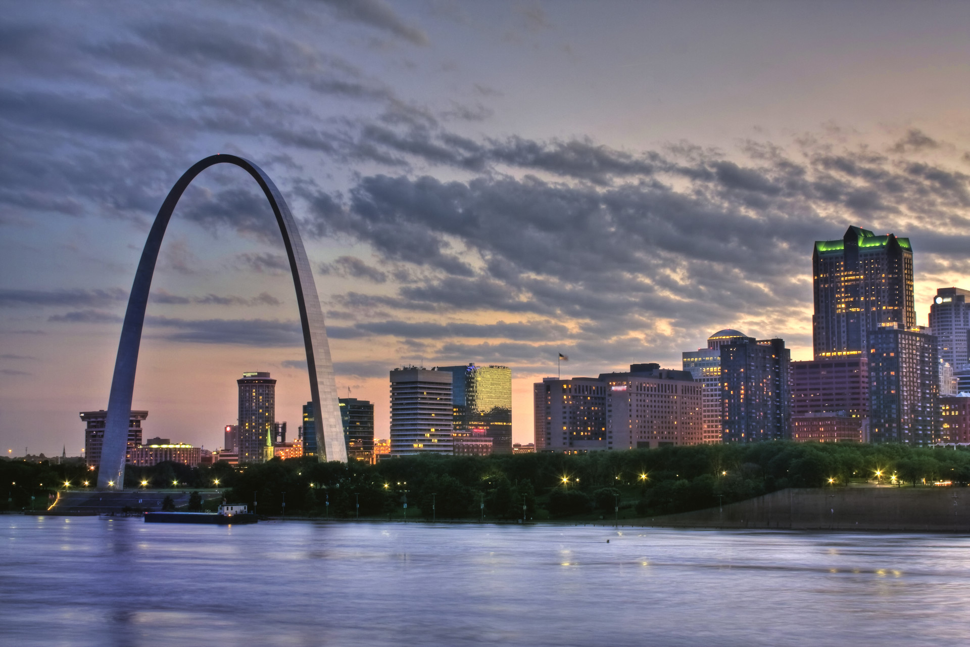 The St. Louis city skyline at dusk, featuring the iconic Gateway Arch and the Mississippi River.