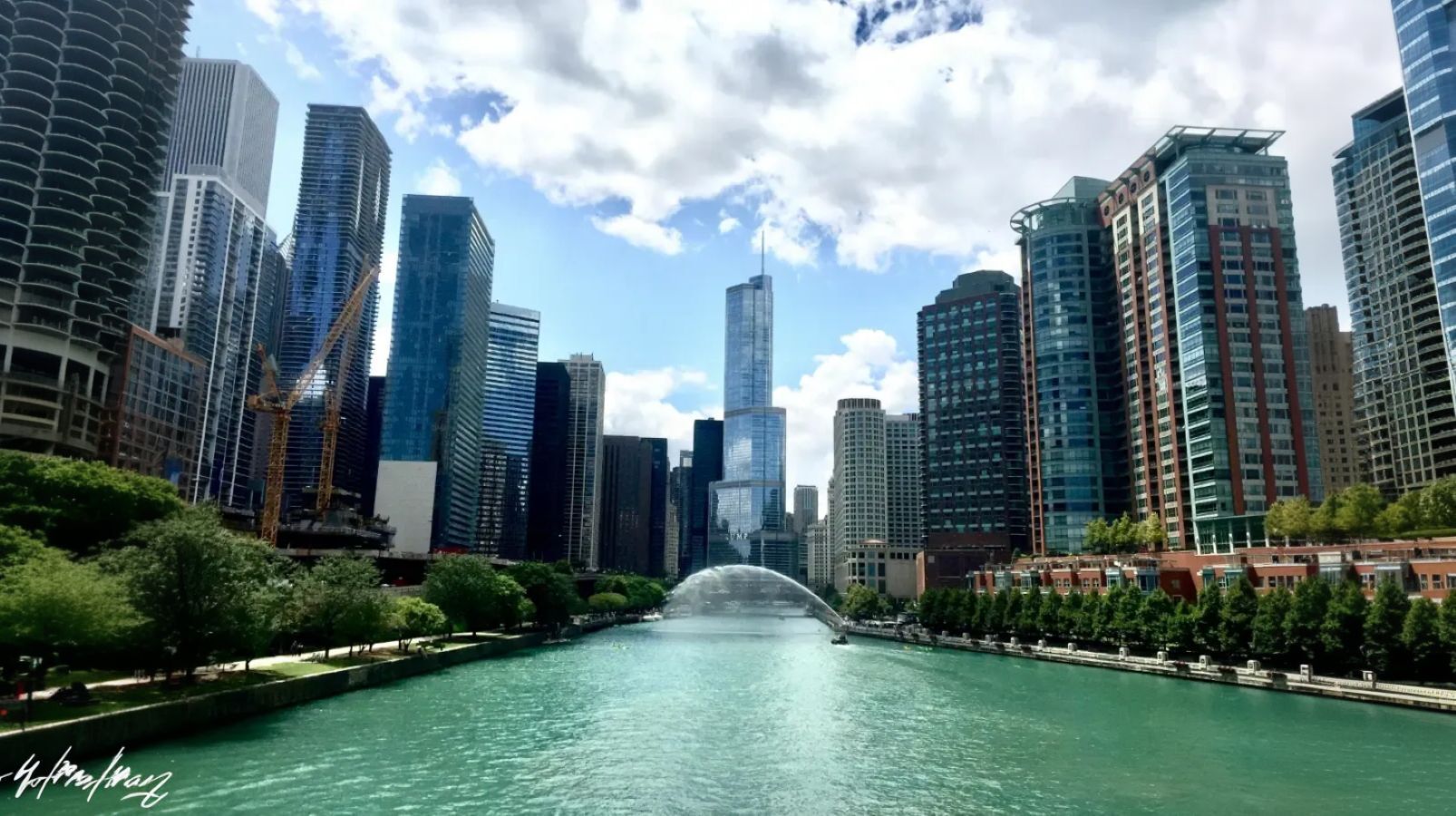 A wide shot of a bustling city skyline with tall, modern skyscrapers lining a prominent turquoise-colored river. The image represents a major urban real estate market, highlighting the dense and dynamic environments where a sale-leaseback offers homeowners a modern solution.